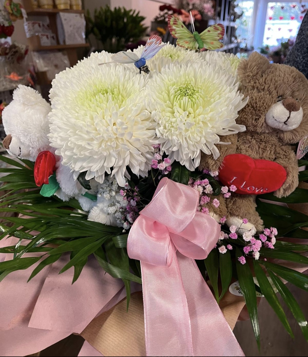 Weiße Chrysanthemen mit zwei Teddybären und Schmetterlingsdeko