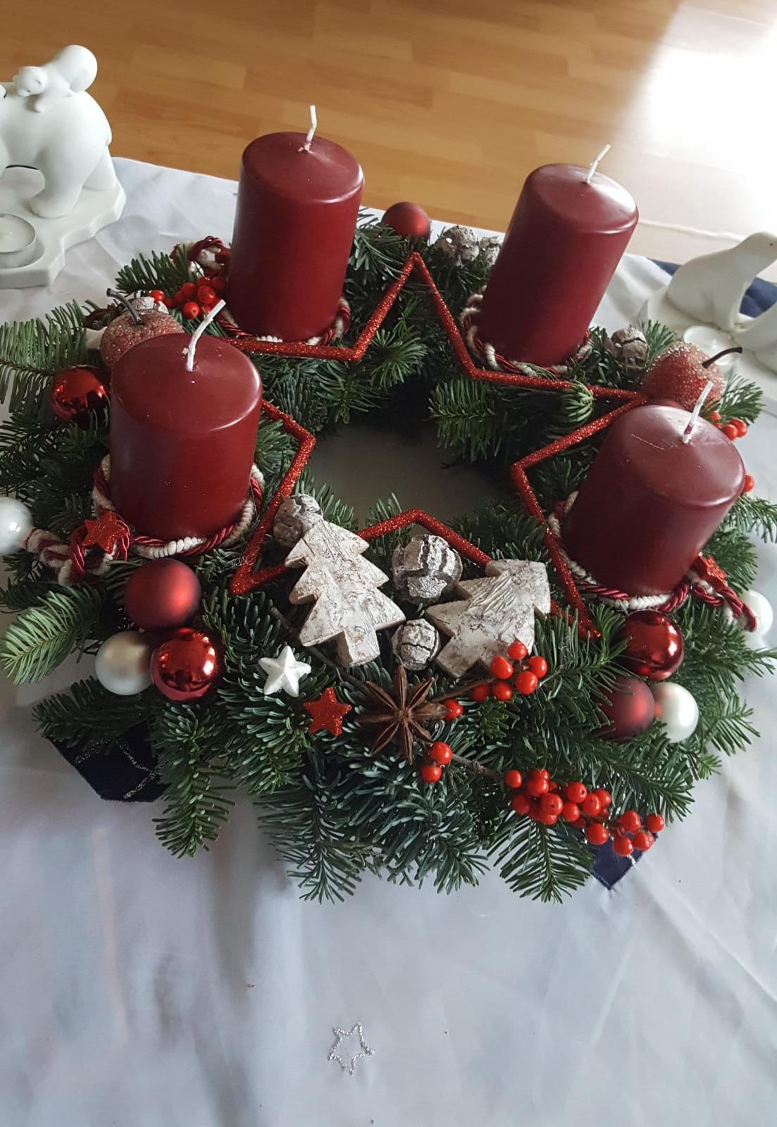 Adventskranz mit vier roten Stumpenkerzen und winterlicher Deko